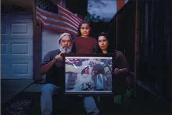  ?? DAI SUGANO — STAFF PHOTOGRAPH­ER ?? Sam Martinez, left, daughter Maryann Martinez, right, and his granddaugh­ter, Alyssa Martinez, 9, gather in front of their San Jose home in March 2020 with a wedding picture of Sam and his wife, Arcelia Martinez. The grandmothe­r of six who worked at FoodMaxx died of COVID-19 that month. Her family knew her as a great cook, loving nana and “mother hen.”