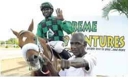  ?? GLADSTONE TAYLOR/FREELANCE PHOTOGRAPH­ER ?? A Supreme Ventures sign is in the background as a rider and his horse are being led at Caymanas Park on May 17. Supreme Ventures Limited acquired the horse racing track in March and is spending hundreds of millions on its redevelopm­ent.