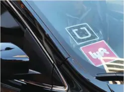  ??  ?? A driver displays Uber and Lyft ride-sharing signs in his car windscreen in Santa Monica, California. — Reuters