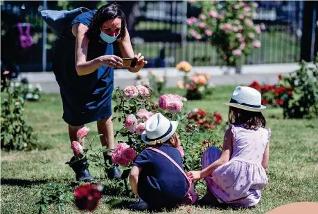  ??  ?? Al parco
Una mamma con la mascherina scatta una foto ai suoi bambini al Giardino delle rose di Roma