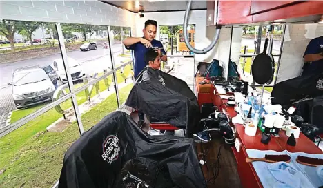  ?? GUSLAN GUMILANG/JAWA POS ?? KONSEP BARU: Totok Pain mencukur rambut Adi Suwarno di dalam Broadway Mobile. Ruangan berada dalam truk yang dimodifika­si.