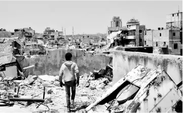  ??  ?? A Syrian boy walks amid the rubble of destroyed buildings in the northern city of Aleppo, which was recaptured by government forces in December 2016. — AFP photo