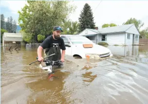  ?? CP PHOTO ?? Resident Kyle Piper carries his bike from his house through the floodwater­s in Grand Forks on Thursday.