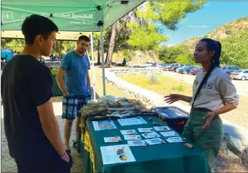  ?? COURTESY OF THE U.S. FOREST SERVICE ?? Field ranger Samantha Carranza provides informatio­n to forest visitors at the Oaks Picnic Area in the San Gabriel Mountains National Monument in July. The field ranger program will be doubled starting in May.
