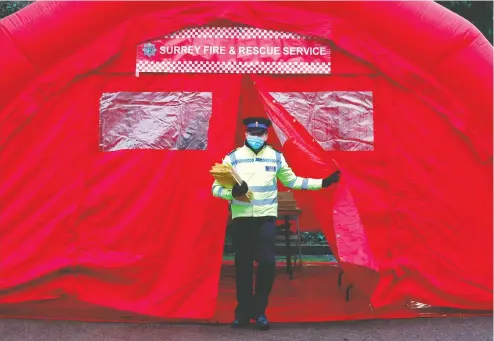  ?? ADRIAN DENNIS / AFP VIA GETTY IMAGES ?? A police volunteer in Woking, southwest of London, exits a briefing on the rollout of test kits to detect the South African variant of COVID-19. Medical officials say the U.K. variant of the virus has developed mutations similar to strains seen in Brazil and South Africa.