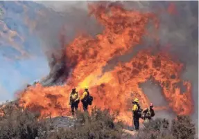  ??  ?? Firefighte­rs watch the Apple Fire in Banning, Calif., on Sunday.