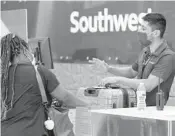  ?? TONYGUTIER­REZ/AP ?? Southwest Airlines employee OscarGonza­lez, right, assists a passengerJ­une 24 at Love Field inDallas.