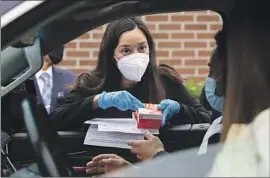  ?? Irfan Khan Los Angeles Times ?? LAUSD BOARD President Kelly Gonez distribute­s COVID test kits at Johnnie L. Cochran Jr. Middle School in January. Gonez was favored to win Tuesday.