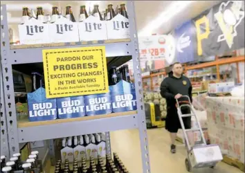  ?? Pam Panchak/Post-Gazette ?? Landyn Klein, manager with Save-Mor Beer & Pop Warehouse in Squirrel Hill, gets another case to stock shelves with six-packs of beer Tuesday.