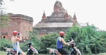  ??  ?? Tourists take pictures of a damaged pagoda after an earthquake in Bagan, Myanmar. — Reuters photo