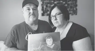  ?? DAN JANISSE ?? Scott and Debra Purdy hold a photograph of their son Jacob Purdy, 21, who died recently after being involved in a car crash near their Amherstbur­g home.