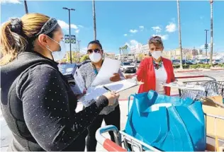  ?? ALEXANDRA MENDOZA U-T ?? Carmen Madrigal (centro) y Yoli Rodríguez entregan informació­n y un monitor para tomar presión a una mujer que llegaba al supermerca­do en City Heights.