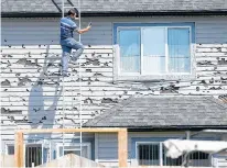  ?? POSTMEDIA ?? Mohammad Roshid from TR Exteriors Ltd. inspects a hail-damaged home in Saddle Ridge, Alta., on June 25.