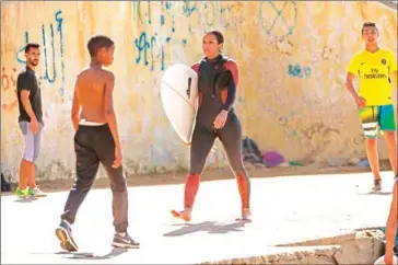  ?? SENNA/AFP FADEL ?? Rim, a female Moroccan surfer walks along the beachside after a surf session in Rabat on April 1.