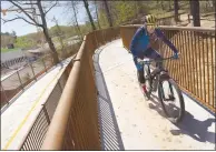  ?? Charlie Kaijo/NWA Democrat-Gazette ?? A bike rider passes Thursday, April 11 along the pedestrian bridge at the one-mile mark for the All-American Mountain Bike Trail in Bentonvill­e.