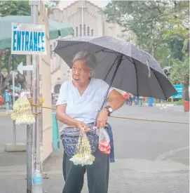  ?? PHOTOGRAPH BY DIANNE BACELONIA FOR THE DAILY TRIBUNE ?? VENDORS outside the Baclaran Church sell, among others, fresh flowers (Sampaguita) and other displays to passersby unmindful of the showers.