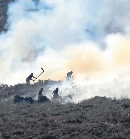  ??  ?? Firefighte­rs tackle the wildfire on Saddlewort­h Moor which continues to spread, and above right, the public get face masks in Calico Crescent, Stalybridg­e, near the blaze on the moor.