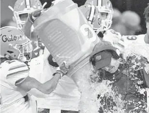  ?? MIKE STEWART/AP ?? UF head coach Dan Mullen gets a celebrator­y drenching during the last seconds of the Peach Bowl. Florida earned a 41-15 win over Michigan.