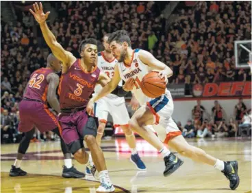  ?? AP PHOTO/LEE LUTHER JR. ?? Virginia guard Ty Jerome dribbles past Virginia Tech defender Wabissa Bede during the first half Monday in Blacksburg, Va. The No. 3-ranked Cavaliers won 64-58.