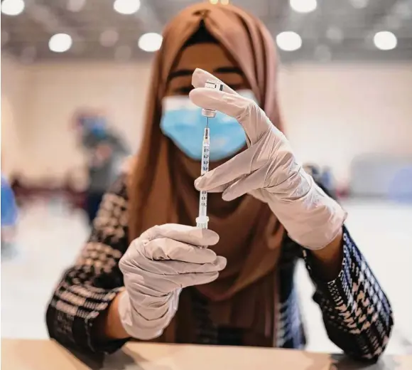  ?? Hannah Beier/Bloomberg file ?? A health care worker prepares a booster dose of the Pfizer-BioNTech COVID-19 shot at a vaccine clinic in Lansdale, Pa.