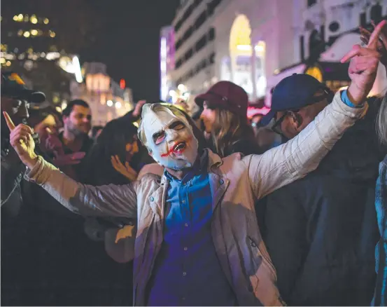  ??  ?? A Halloween reveller enjoys a last taste of freedom in Leicester Square in London before a four-week lockdown in England, announced by PM Boris Johnson (inset). Pictures: GETTY IMAGES, AFP