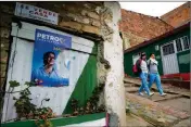 ?? ASSOCIATED PRESS ?? NEIGHBORS PASS BY a campaign poster of presidenti­al candidate Gustavo Petro at “Bolivar 83” community in the town of Zipaquira, north of Bogota, Colombia, Saturday.