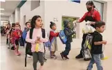  ?? Kin Man Hui/staff photograph­er ?? A cafeteria staffer hands out breakfast meals to pre-k students at Menchaca Early Childhood Center at Southside ISD.