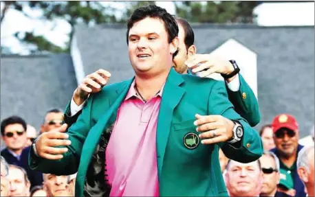  ?? AFP ?? Patrick Reed is presented with the green jacket by previous champion Sergio Garcia after winning the 2018 Masters at Augusta National in Georgia on Sunday.