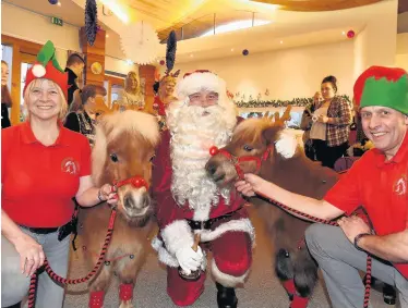  ??  ?? SANTASTIC Elf helpers and Shetland ponies join Father Christmas on his rounds handing out gifts at Robin House