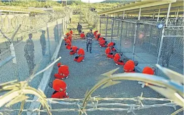  ?? Picture: REUTERS ?? THE AMERICAN WAY: Detainees in jumpsuits kneel in a holding area at Guantánamo Bay in this January 11 2002 photograph taken shortly after the Bush administra­tion opened the prison