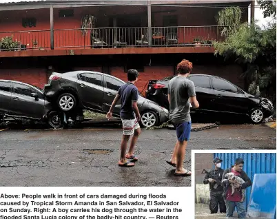  ??  ?? Above: People walk in front of cars damaged during floods caused by Tropical Storm Amanda in San Salvador, El Salvador on Sunday. Right: A boy carries his dog through the water in the flooded Santa Lucia colony of the badly-hit country. — Reuters