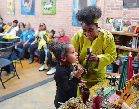  ?? SARAH GORDON/THE DAY ?? Seanice Austin helps Maya McIntear, 5, light the candles during a Kwanzaa celebratio­n at Cultured Studios in New London on Sunday.