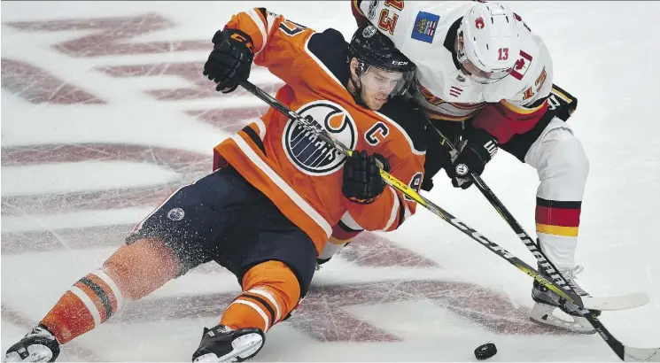  ?? ED KAISER ?? Edmonton Oilers centre Connor McDavid gets taken down by Calgary Flames left wing Johnny Gaudreau during the season opener at Rogers Place on Wednesday night.