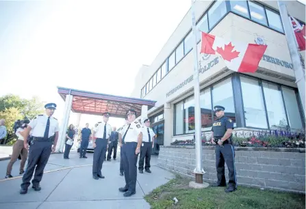  ?? JASON BAIN/EXAMINER ?? Police officers stand for a moment of silence after Peterborou­gh County OPP Const. Jason Folz lowered the flag at city police headquarte­rs to half mast to mark Internatio­nal Overdose Awareness Day on Thursday.