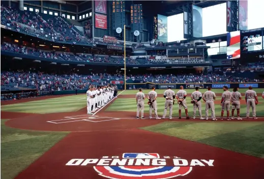  ?? PHOTOS BY PATRICK BREEN/THE REPUBLIC ?? The Diamondbac­ks and Reds line up for the national anthem before Arizona’s home opener at Chase Field in Phoenix.