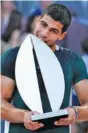  ?? AP PHOTO BY PAUL WHITE ?? Carlos Alcaraz jokingly bites his trophy after beating Alexander Zverev to win the Madrid Open earlier this month.