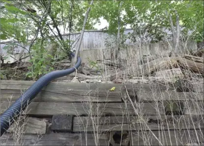  ??  ?? A retaining wall of railway ties was installed behind Donna Dobroski’s house. It was later reinforced with concrete blocks, above.