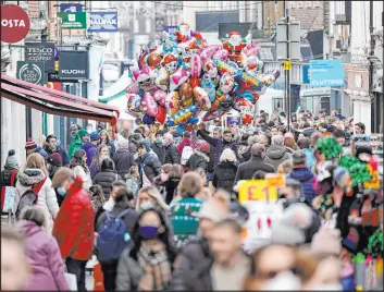  ?? Andrew Matthews The Associated Press ?? Christmas shoppers make their way Tuesday along High Street in Winchester, England. The government Monday warned of possible new COVID restrictio­ns.