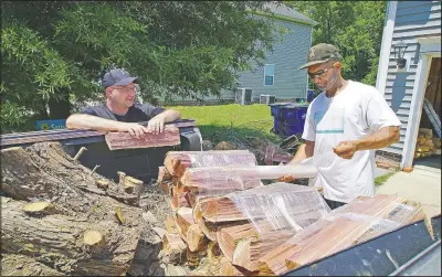  ?? (AP/Allen G. Breed) ?? Alton Lucas (right) wraps firewood for sale as he and neighbor Ryan Isaac, a correction­al officer, chat outside Lucas’ home outside of Raleigh, N.C.