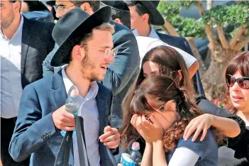  ?? — AFP ?? An Ultra-Orthodox Jewish woman comforts another at a cemetary in Benei Brak, as people attend the funeral of one of the victims of a stampede, when tens of thousands of people were gathered to celebrate the festival of Lag Baomer at a site in Meron in northern Israel early on Friday.