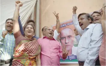  ?? — AFP ?? Friends of Kulbhushan Jadhav react after he was given a stay of execution in the neighbourh­ood where he grew up in Mumbai on Thursday.