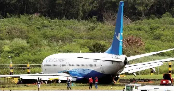  ??  ?? Rescue workers stand near the Xiamen Air Boeing 737-800 after it skidded off the runway at Ninoy Aquino Internatio­nal airport in Paranaque, Metro Manila, in the Philippine­s. —Reuters photo
