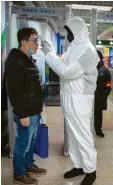  ?? Foto: dpa ?? In einer U-Bahn-Station in Peking misst ein Bedienstet­er mit Schutzanzu­g die Temperatur eines Fahrgastes.