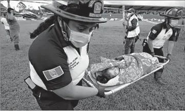  ?? MOISES CASTILLO/AP ?? Guatemalan rescue: A girl is carried to a waiting ambulance Saturday in San Cristobal Verapaz, where residents are believed buried by a massive, rain-fueled landslide in the aftermath of Tropical Storm Eta. Rescue teams first had to overcome landslides and deep mud just to reach the site where officials estimate some 150 homes were devastated.