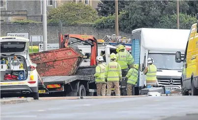  ??  ?? Emergency services attempt to get the driver of the skip lorry out of his cab. Picture: Kim Cessford.