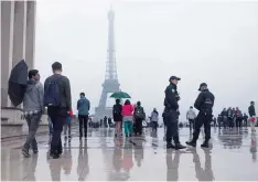  ??  ?? PARIS: People walk past by French police officers, as they patrol at Trocadero plaza with the Eiffel Tower in the background in Paris yesterday. —AP