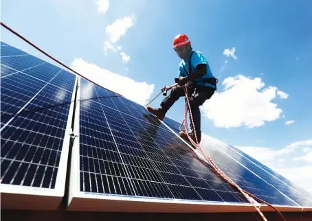  ?? Reuters ?? A worker sets up solar panels on the roof of a home in Colmenar Viejo, Spain. Some Spanish renewable energy firms are offering to install panels for free.