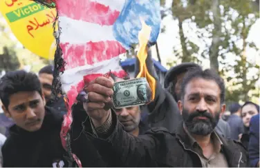  ?? Atta Kenare / AFP / Getty Images ?? On the eve of renewed U.S. sanctions, a demonstrat­or burns a U.S. dollar bill at a rally in Tehran.