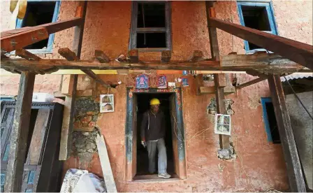  ??  ?? Salvage operation: A worker walking out of an earthquake-damaged house secured for retrofitti­ng in the village of Dungkharka in Kavre district, Kathmandu. — AFP