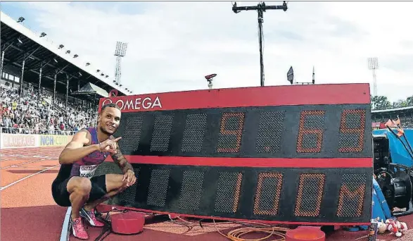  ?? JONATHAN NACKSTRAND / AFP ?? Andre de Grasse posa junto al cronómetro que refleja sus 9s69 de ayer, una marca que el viento anuló: había 4,8 m/s a favor